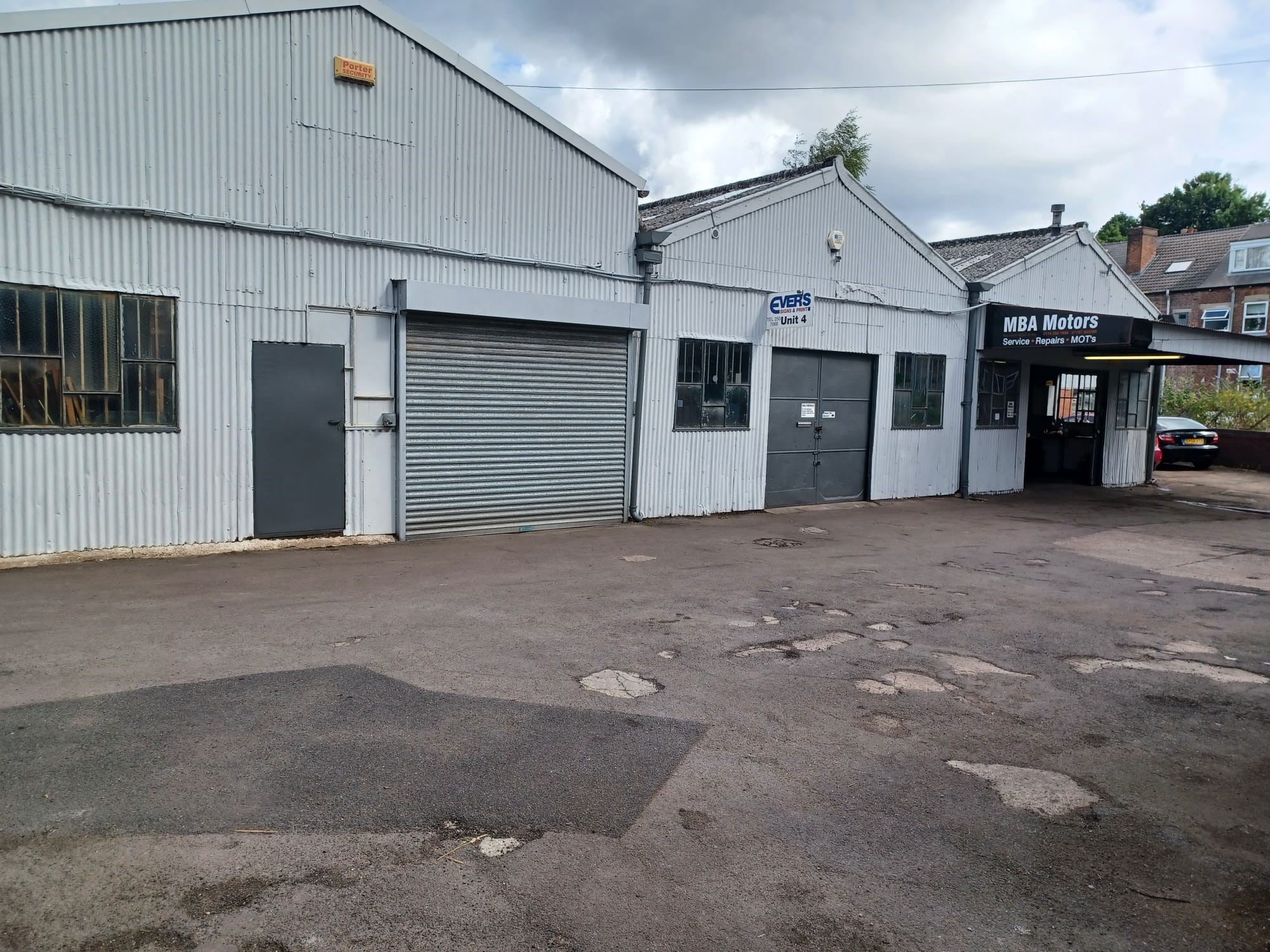 Row of yard-side workshop units with roller shutter and business entrances